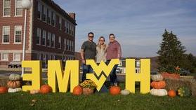 A family standing around the H-O-M-E letters on campus